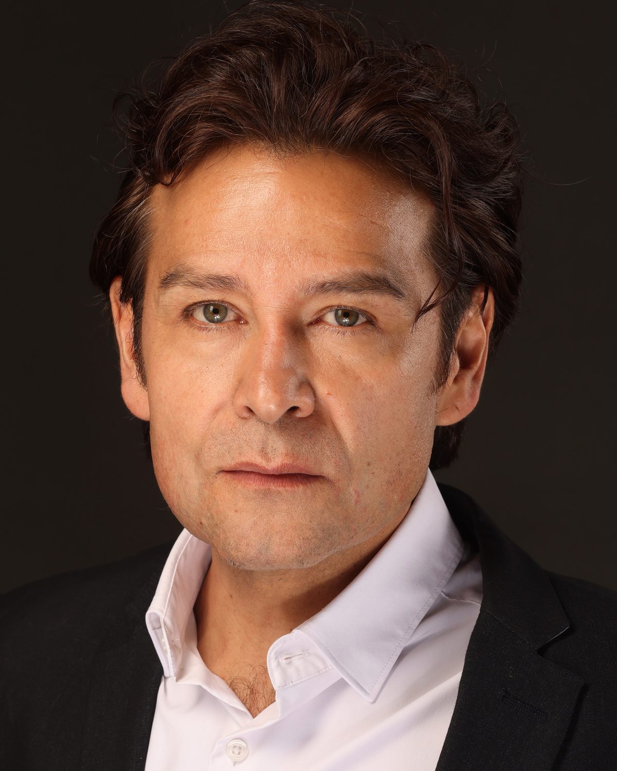 Retrato de Tizoc Arroyo, actor mexicano, con camisa blanca y saco oscuro